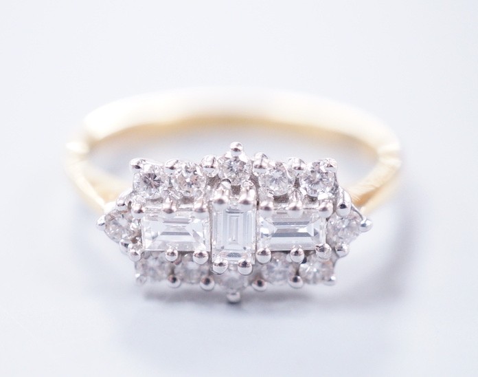 A modern 18ct gold, baguette and round cut diamond set shaped cluster ring, size O/P, gross weight 4.1 grams